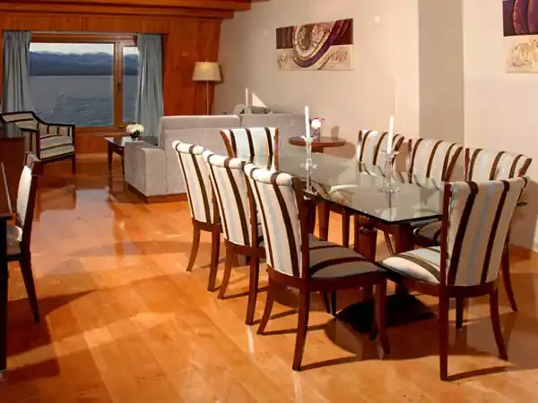 Luxurious suite dining area at Alma del Lago with striped chairs, glass table, and panoramic lake views through floor-to-ceiling windows.
