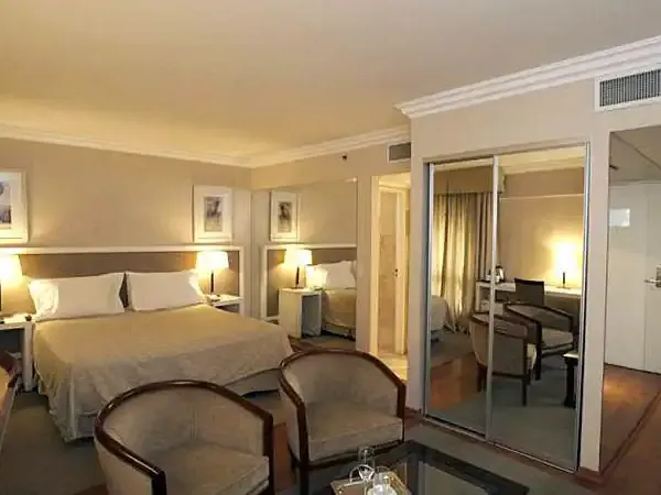 Luxurious hotel suite at Huentalá with elegant bedroom, sitting area, and modern amenities in warm neutral tones.