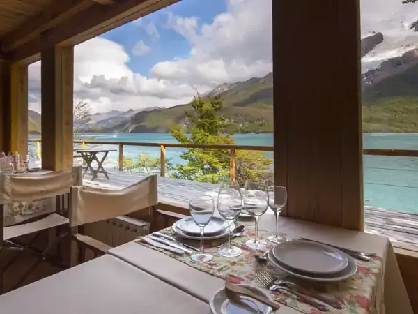 Elegant dining room at Aguas Arriba Lodge overlooking turquoise lake waters surrounded by snow-capped Patagonian mountains.