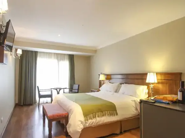 Luxurious hotel bedroom at Chalten Suites with elegant furnishings, modern amenities, and warm lighting overlooking mountain views.