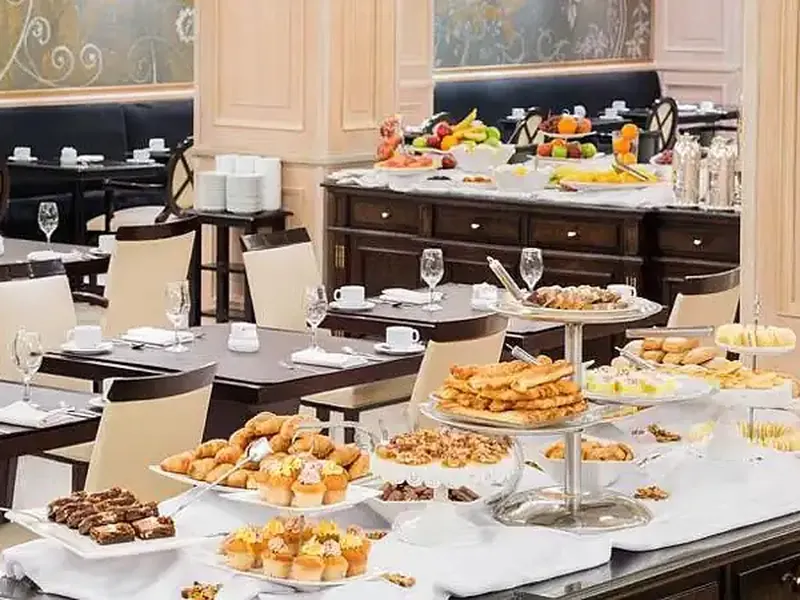 Elegant diplomatic reception room in Buenos Aires with tiered pastries, fresh fruit displays, and formal dining setup.