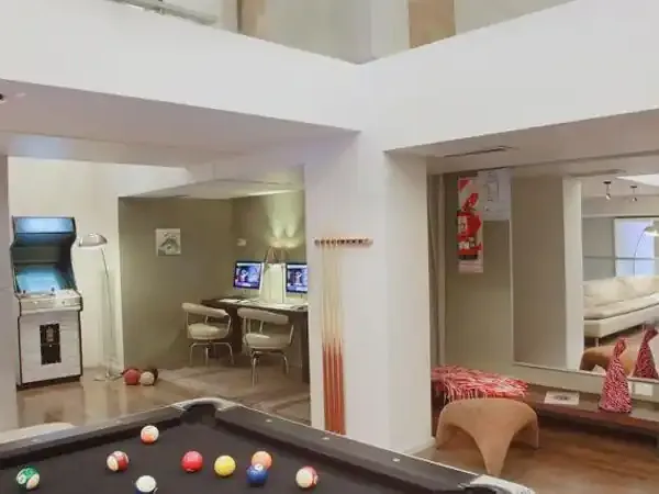 Modern recreational game room at Esplendor hotel with billiards table, arcade games, and lounge seating.