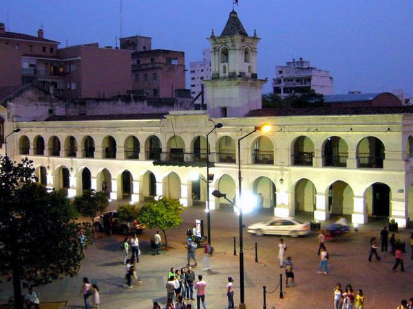 Illuminated colonial Cabildo building with arched facade in Salta's historic plaza at dusk, surrounded by locals and visitors.