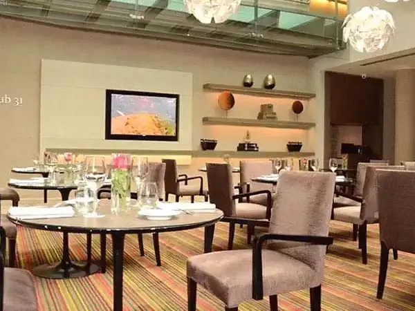 Elegant dining room at Club 31 in Buenos Aires' Recoleta neighborhood featuring round tables, modern décor, and ambient lighting.