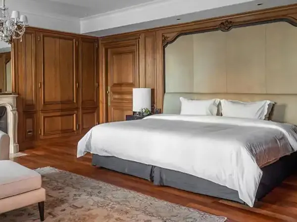 Luxurious bedroom suite at Park Hyatt featuring wooden cabinetry, cream upholstered headboard, and elegant furnishings.