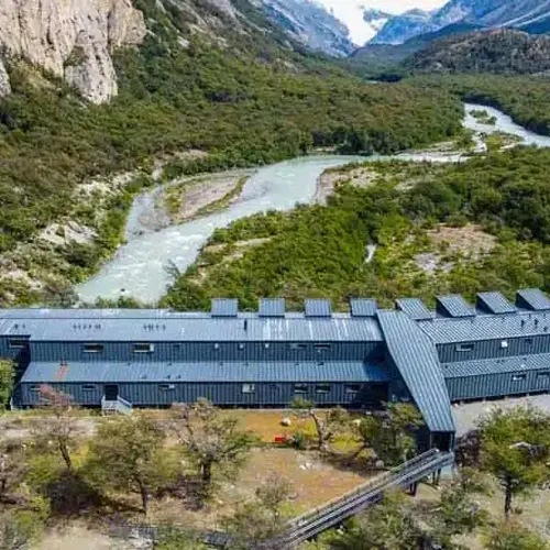 Modern lodge with turquoise river and mountain peaks in remote Patagonian wilderness near Chaten.