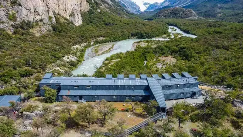Modern lodge with turquoise river and mountain peaks in remote Patagonian wilderness near Chaten.