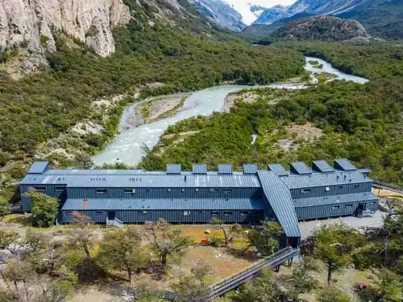 Modern lodge with turquoise river and mountain peaks in remote Patagonian wilderness near Chaten.