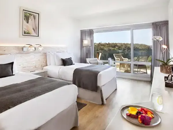 Spacious modern hotel room at Gran Meliá Iguazú with twin beds, panoramic forest views, and contemporary amenities overlooking the Iguazú region.