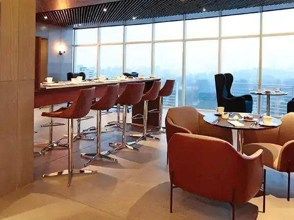 Luxury high-rise restaurant with panoramic city views, elegant red chairs, and modern dining setup at DoubleTree by Hilton.