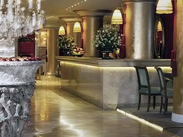 Elegant hotel lobby in Buenos Aires featuring marble columns, crystal chandelier, and polished floors with sophisticated architectural design.