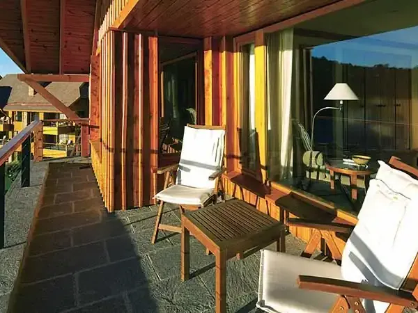 Luxury lodge terrace at Llao Llao with mountain views, wooden furniture, and Patagonian landscape at sunset.