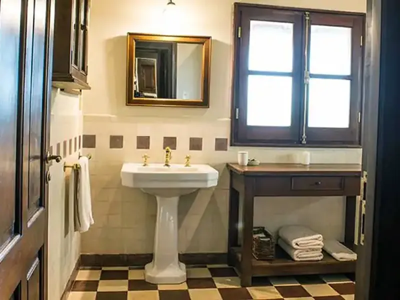 Elegant vintage bathroom with pedestal sink, checkered tile floor, and period fixtures at Rincón del Socorro luxury estancia.