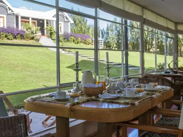 Elegant dining room at Los Ponchos with panoramic windows overlooking manicured gardens and Patagonian landscape.