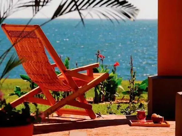 Bright red wooden chair overlooking turquoise ocean waters at a coastal Patagonian retreat in Puerto Valle.