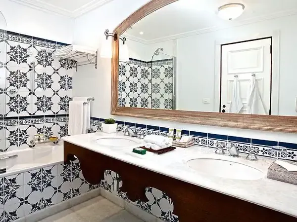 Luxurious bathroom with black and white patterned tiles, double vanity, and wooden-framed mirror at Belmond hotel.