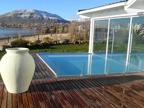 Modern lakeside lodge with heated pool overlooking Nahuel Huapi Lake and snow-capped volcano in Bariloche, Patagonia.