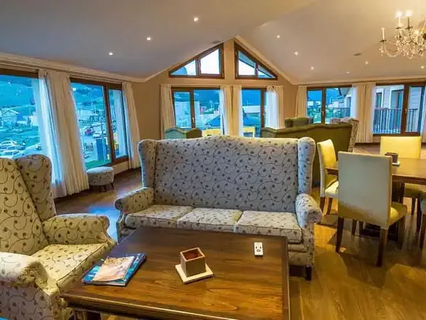 Luxurious open-plan lounge at El Chaltén Suites with panoramic mountain views, elegant furnishings, and floor-to-ceiling windows overlooking Patagonia.