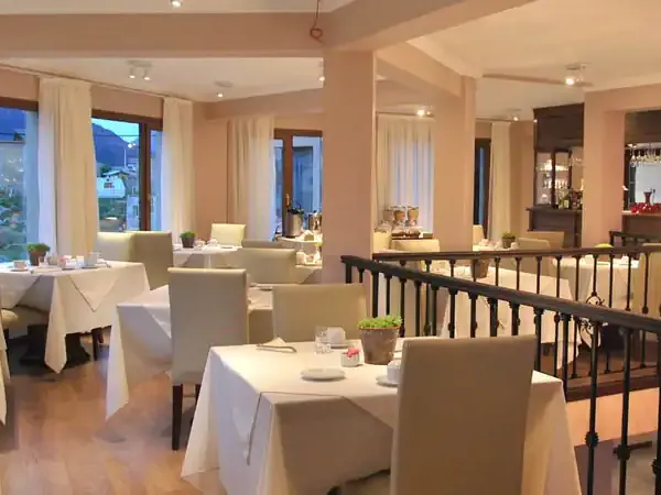 Elegant fine dining restaurant at Chalten Suites with white-clothed tables, upholstered chairs, and panoramic windows overlooking El Chalten.