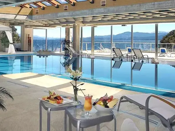 Luxurious indoor swimming pool at Incayal resort with panoramic lake and mountain views through floor-to-ceiling windows.