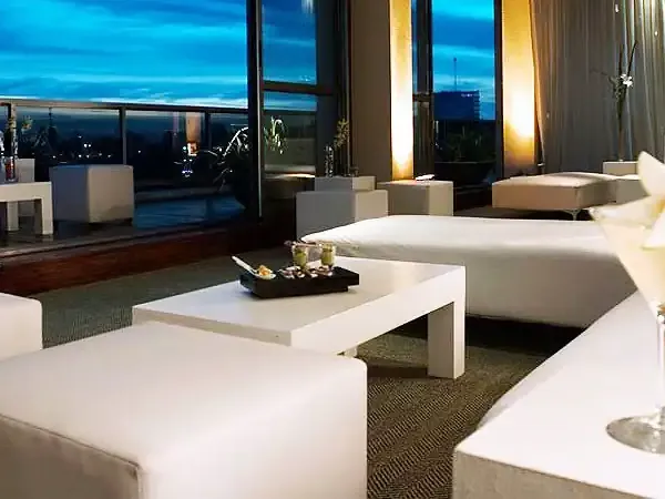 Luxury high-rise suite in Buenos Aires with panoramic river views, modern white furnishings, and evening cityscape through floor-to-ceiling windows.