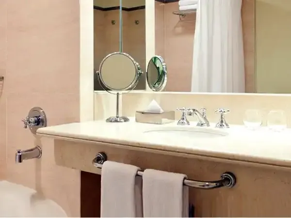 Modern bathroom vanity with white countertop, dual sinks, and circular mirrors at Sheraton hotel.
