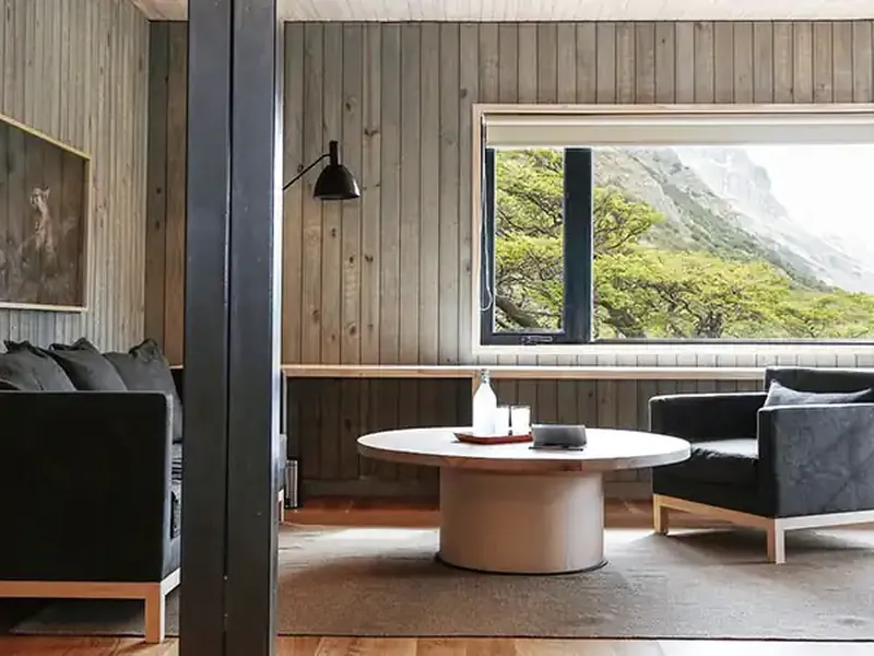 Modern minimalist lodge interior at Explora Chaltén with mountain views, featuring contemporary furniture and floor-to-ceiling windows overlooking Patagonian peaks.