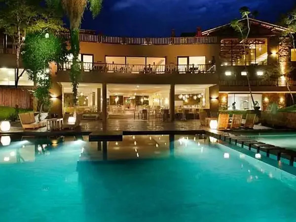 Luxurious resort pool at night with illuminated multi-story building, loungers, and manicured grounds in Patagonia.