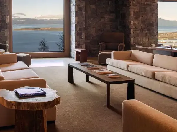 Luxury lounge with floor-to-ceiling windows overlooking Beagle Channel and Ushuaia's mountainous landscape in Patagonia.