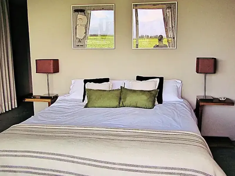 Modern bedroom at Finca La Azul with green cushions, mountain views through windows, and contemporary decor.
