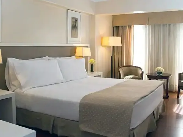 Luxurious hotel bedroom with queen bed, modern furnishings, and large windows overlooking Huentalá in Patagonia.