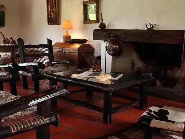 Historic stone lodge interior with dark wooden furniture, fireplace, and traditional Patagonian decor at Aguapé Lodge.