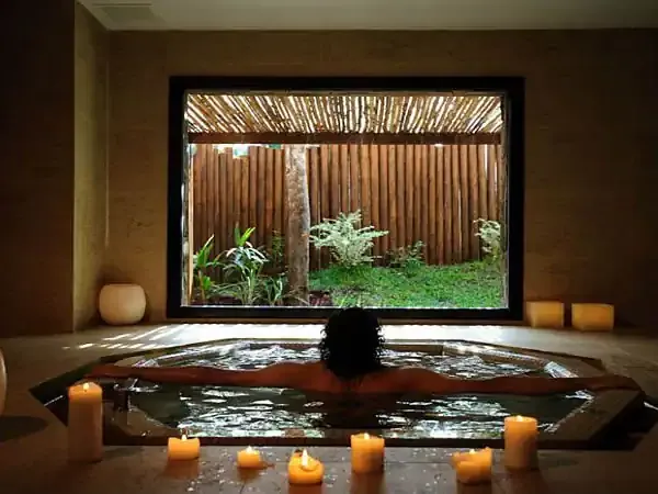 Luxury spa bath with candlelit ambiance overlooking a lush garden courtyard at Loi Suites resort.