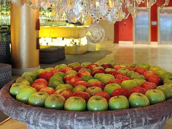 Fresh apples arranged in a rustic bowl at Huentalá hotel lobby with modern décor and crystal chandelier.