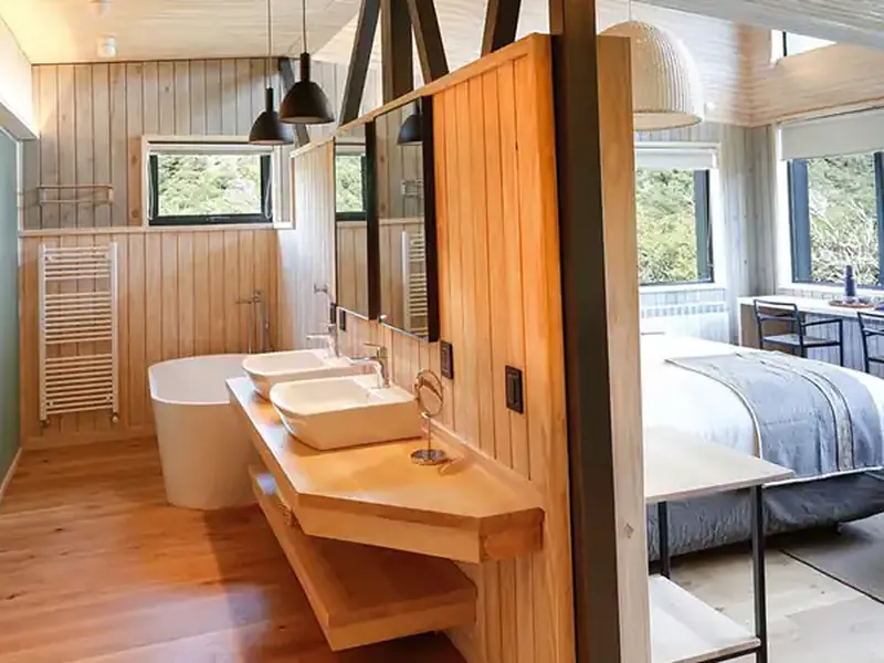 Luxury hotel suite at Explora Chaltén featuring an open-plan bedroom, ensuite bathroom with soaking tub, and panoramic windows overlooking Patagonian landscape.