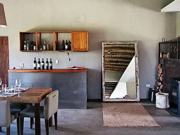 Rustic wine tasting room at Finca La Azul with wooden cabinets, wine bottles, and industrial-style decor in Patagonia.