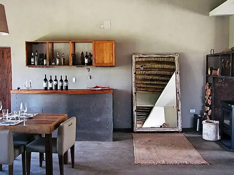 Rustic wine tasting room at Finca La Azul with wooden cabinets, wine bottles, and industrial-style decor in Patagonia.