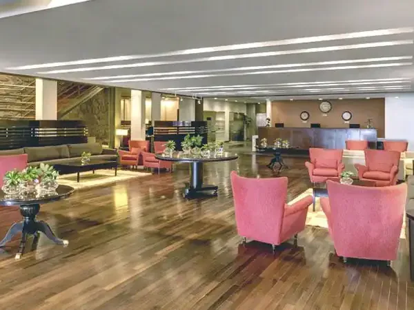 Sheraton hotel lobby with modern pink armchairs, wooden flooring, and contemporary furnishings in a spacious reception area.