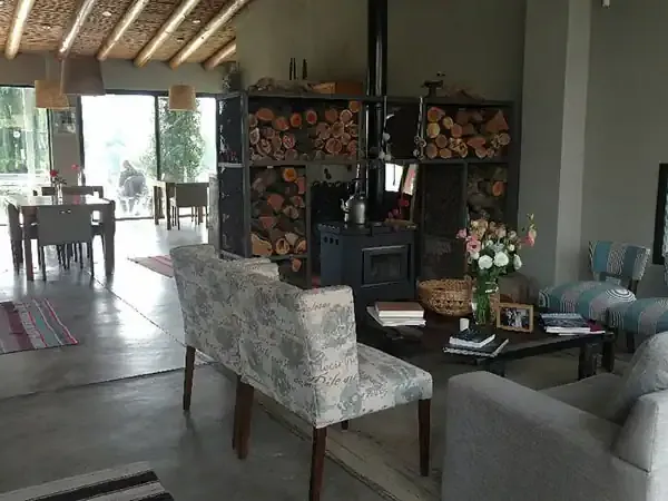 Modern rustic living room at Finca La Azul with fireplace, comfortable seating, and panoramic windows overlooking Patagonian landscape.