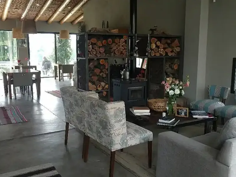 Modern rustic living room at Finca La Azul with fireplace, comfortable seating, and panoramic windows overlooking Patagonian landscape.