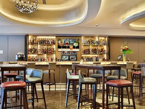 Modern hotel bar lounge at Palladio with elegant seating, illuminated liquor shelves, and contemporary ceiling design.
