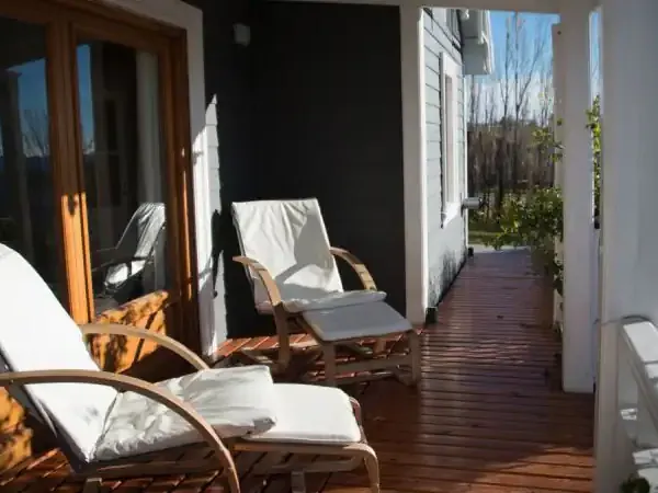Sunny terrace at Los Ponchos with lounge chairs, wooden deck, and Patagonian landscape views.