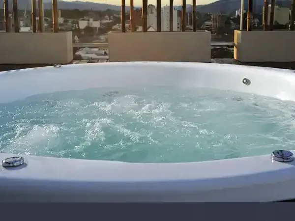Luxury rooftop hot tub with turquoise water overlooking Andean mountains and valley town at sunset.