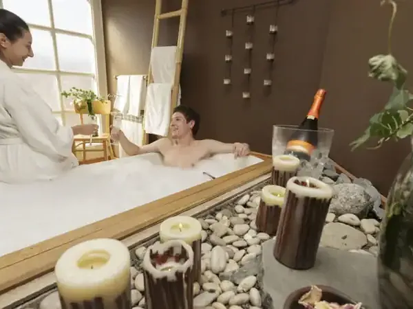 Spa attendant serves champagne to relaxed guest in luxurious thermal bath at Hotel Las Torres.