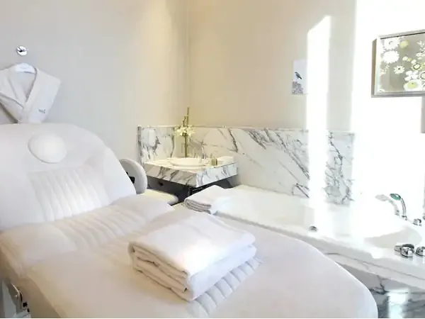 Luxury spa treatment room at Recoleta Grand with marble sink, white massage bed, and natural daylight.