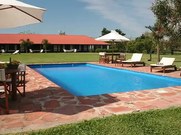 Aguapé Lodge resort pool with loungers, umbrellas, and manicured gardens under clear skies.