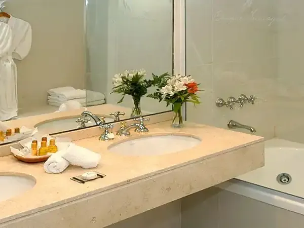 Luxury bathroom at Inca Yal hotel with marble countertop, dual sinks, fresh flowers, and spa amenities.
