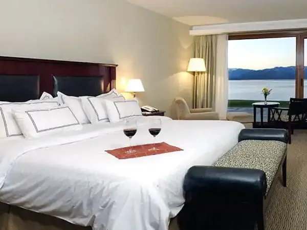 Luxury hotel bedroom with lake views overlooking Nahuel Huapi Lake in Bariloche, featuring premium bedding and modern amenities.