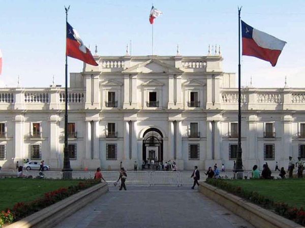 Casa de la Moneda presidential palace in Santiago de Chile with Chilean flags and manicured gardens in front.
