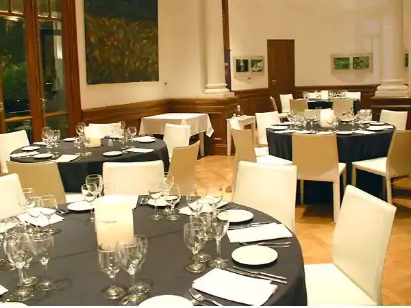 Elegant formal dining room with black tablecloths, cream chairs, and place settings for upscale restaurant or event venue.
